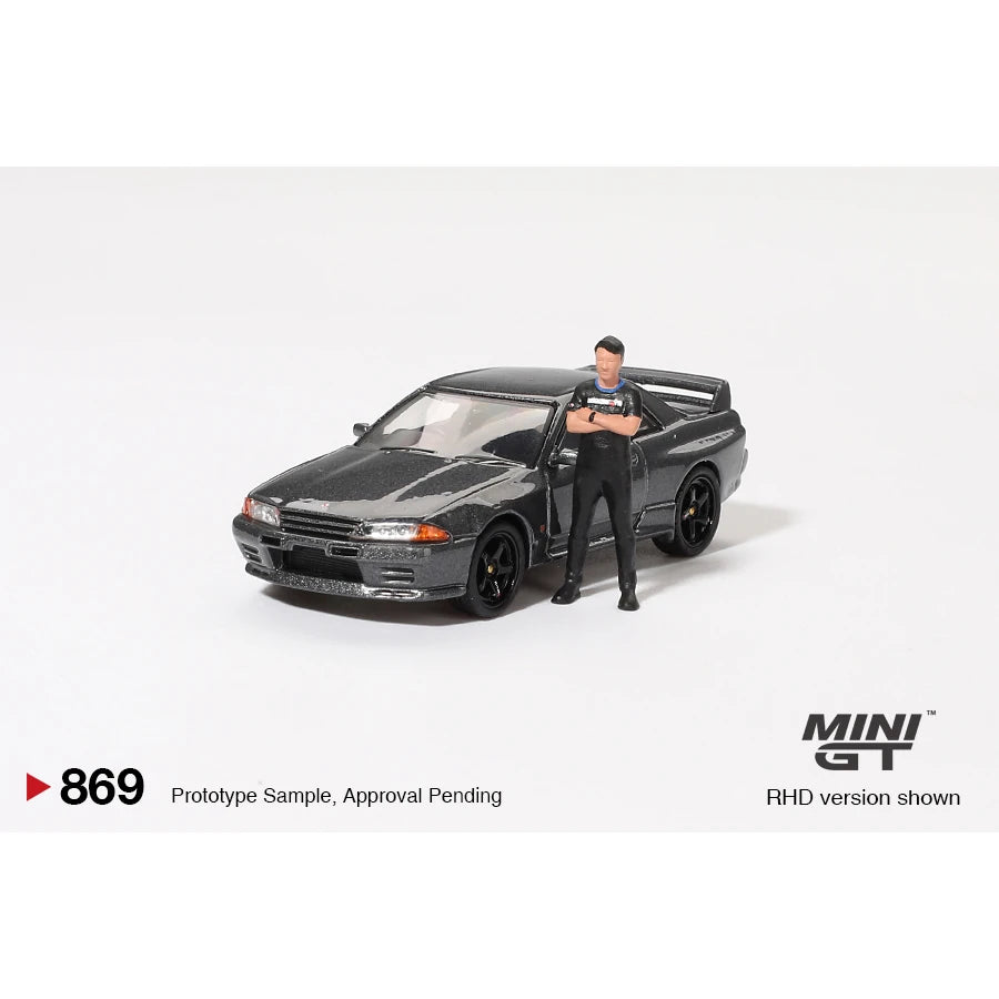 MiniGT 1:64 scale die-cast Nissan Skyline GT-R R32 in Gunmetal with Matsuda figure – model #869